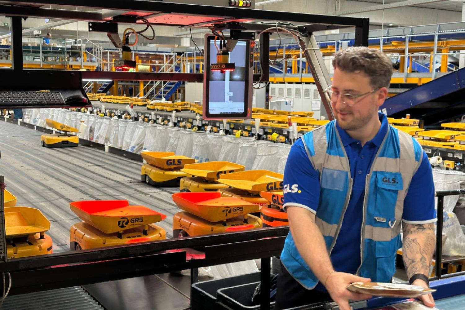 Robots de clasificación autónomos en uso en GLS: un empleado equipa los AGVs autónomos con paquetes en el depósito de Bielefeld. (Foto: GLS Germany)