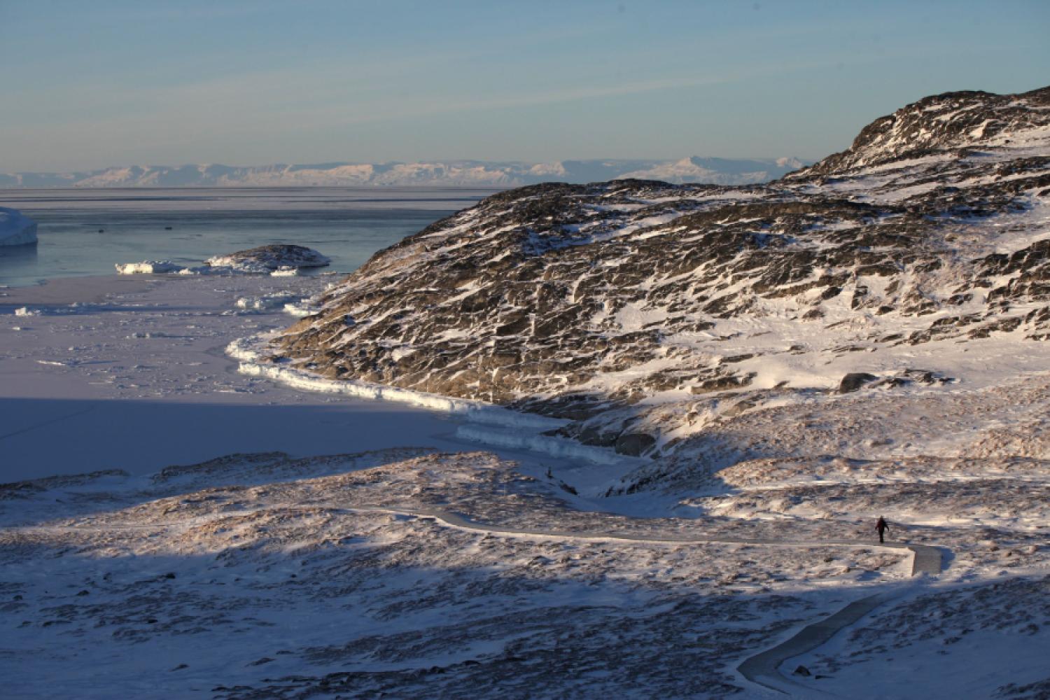 A woman walks through a snowy rocky landscape at the Ilulissat Icefjord in Greenland. Greenland's immense raw material resources have long since attracted the interest not only of US President Trump but also of the EU. (Photo: Steffen Trumpf/dpa)