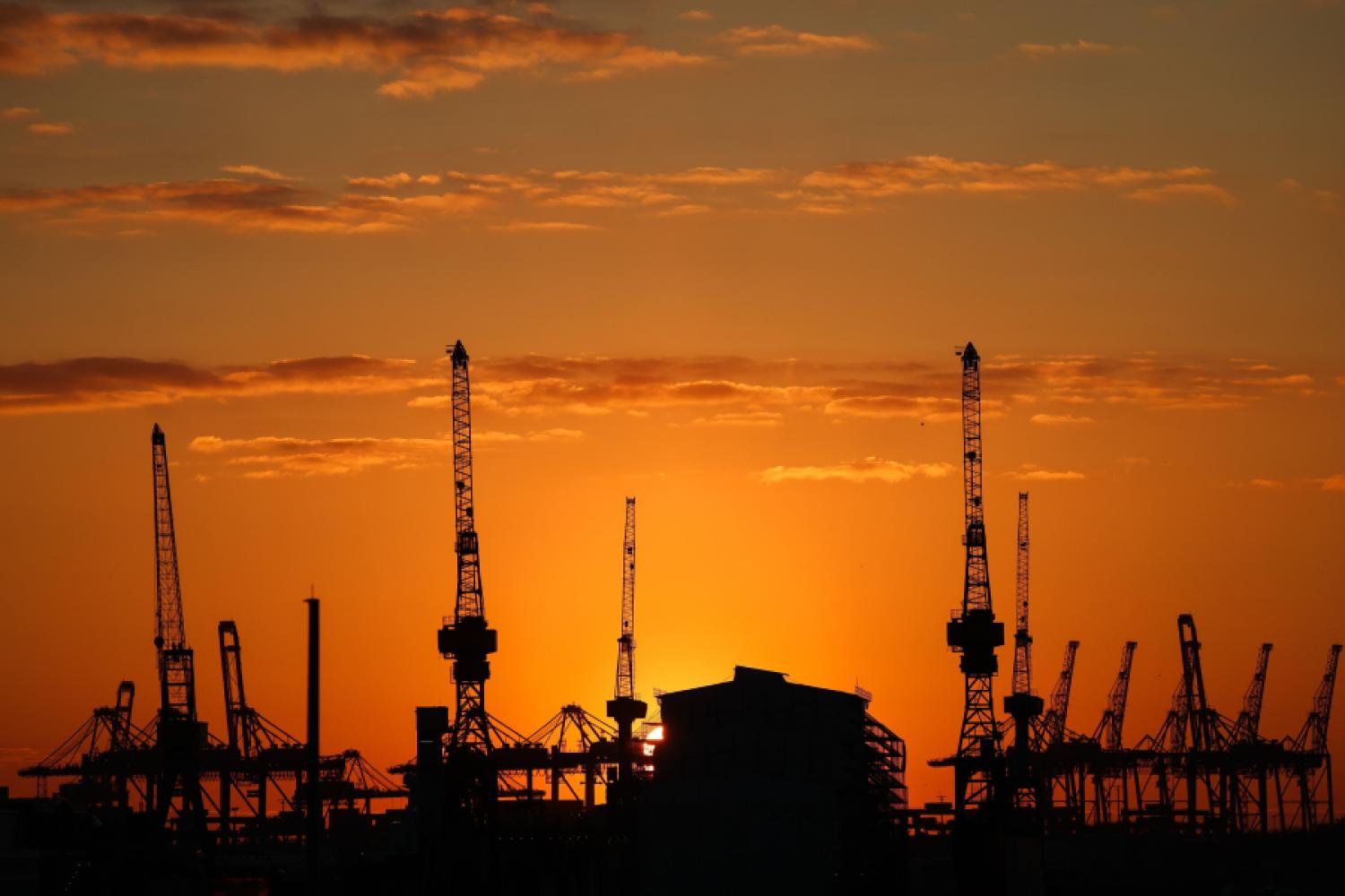 The sun sets behind container bridges and harbor cranes in the Port of Hamburg in February 2025. (Photo: Christian Charisius/dpa)