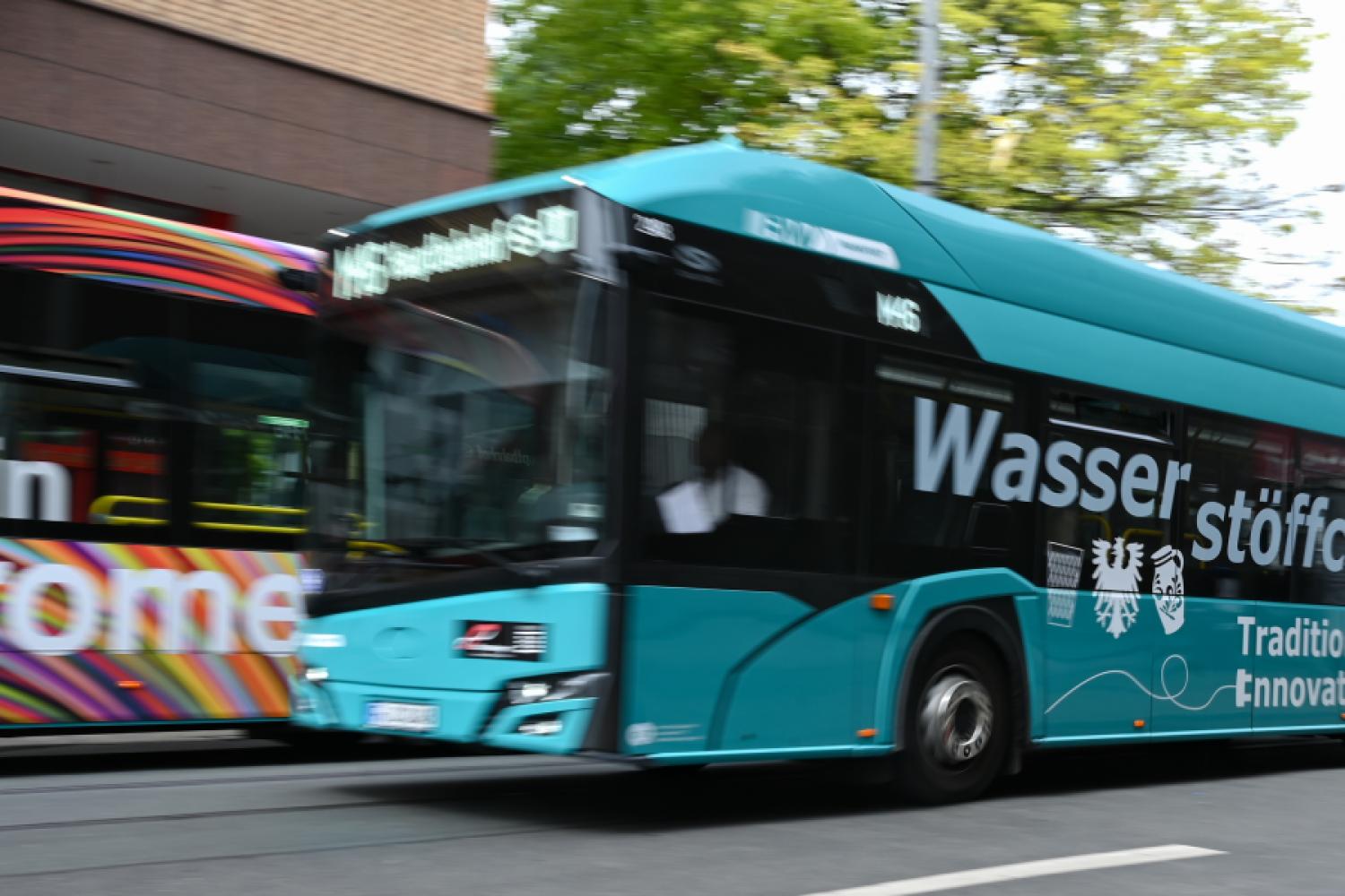 A hydrogen bus on line M46 with the inscription "Wasserstöffche" passes by an electric bus at the main train station. Electric buses are increasingly operating in more and more Hessian cities. Many municipalities and their transport companies want to further advance the transition. | Image: Arne Dedert/dpa.