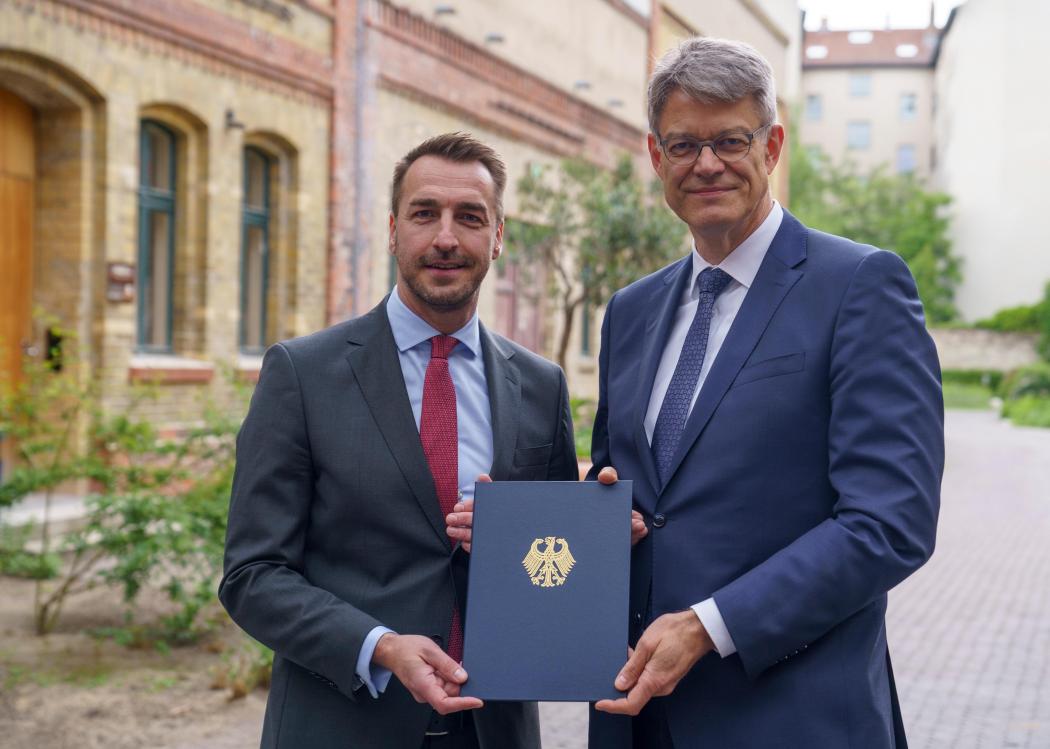 From the hands of Dr. Patrick Schnieder, Federal Minister for Transport (right), Steffen Bauer, CEO of HGK Shipping, received permission for his company to conduct test operations of remotely controlled inland vessels in the German canal network. (Image: Stella Scheibenzuber | HGK Shipping)