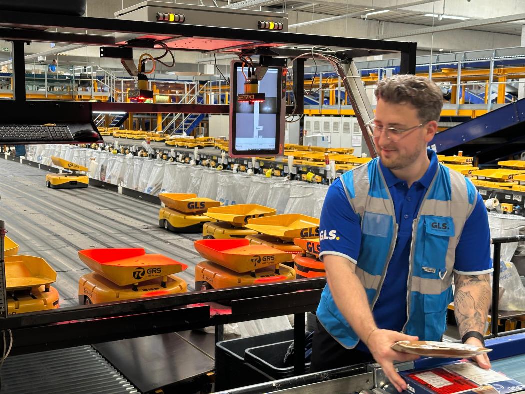 Robots de clasificación autónomos en uso en GLS: un empleado equipa los AGVs autónomos con paquetes en el depósito de Bielefeld. (Foto: GLS Germany)