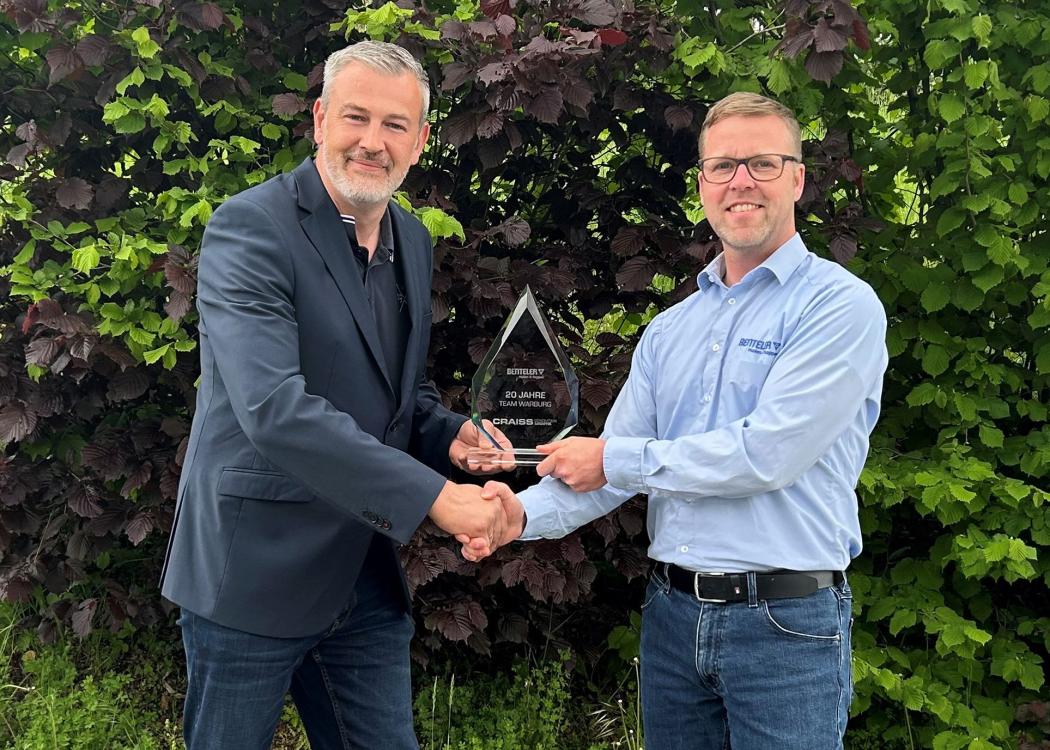 Z okazji dwudziestej rocznicy lokalizacji Craiss w Warburgu, Marco Koltermann (z lewej), kierownik lokalizacji centrum logistycznego Warburg i Kleinenberg w Craiss, wręcza trofeum Ralfowi Schulte (z prawej), menedżerowi logistyki w Benteler w Warburgu. (Foto: Craiss)