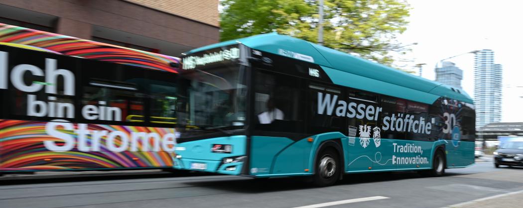A hydrogen bus on line M46 with the inscription "Wasserstöffche" passes by an electric bus at the main train station. Electric buses are increasingly operating in more and more Hessian cities. Many municipalities and their transport companies want to further advance the transition. | Image: Arne Dedert/dpa.